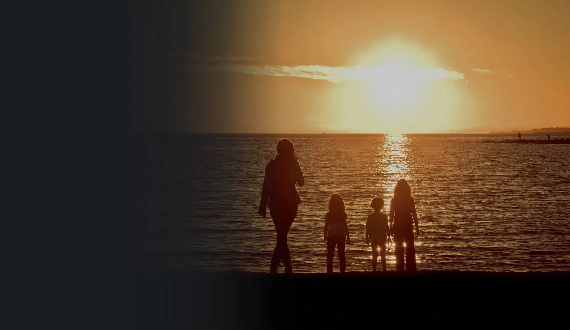 Una madre y sus tres hijos frente al mar al atardecer